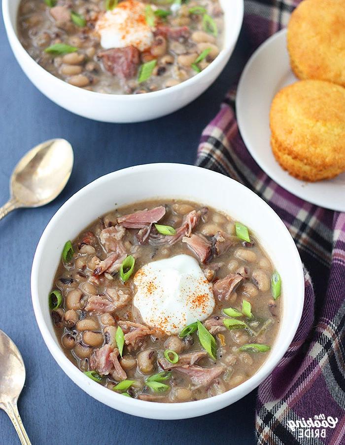 bowl of black eyed pea soup with a dollop of soup cream, sprinkle of cayenne pepper and sliced green onions