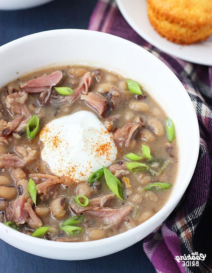 bowl of black eyed pea soup with a dollop of soup cream, sprinkle of cayenne pepper and sliced green onions
