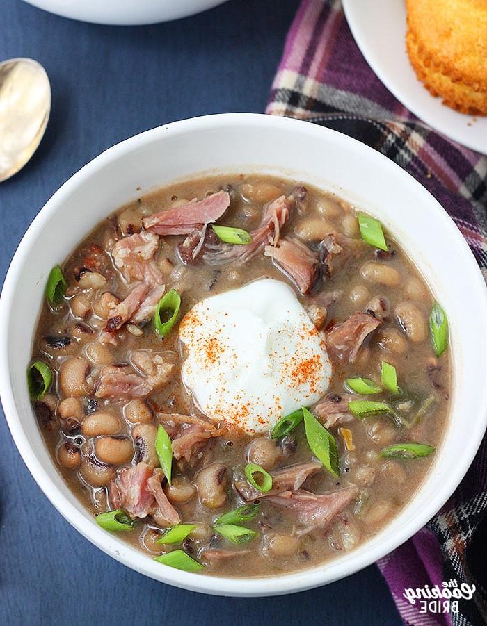 bowl of black eyed pea soup with a dollop of soup cream, sprinkle of cayenne pepper and sliced green onions