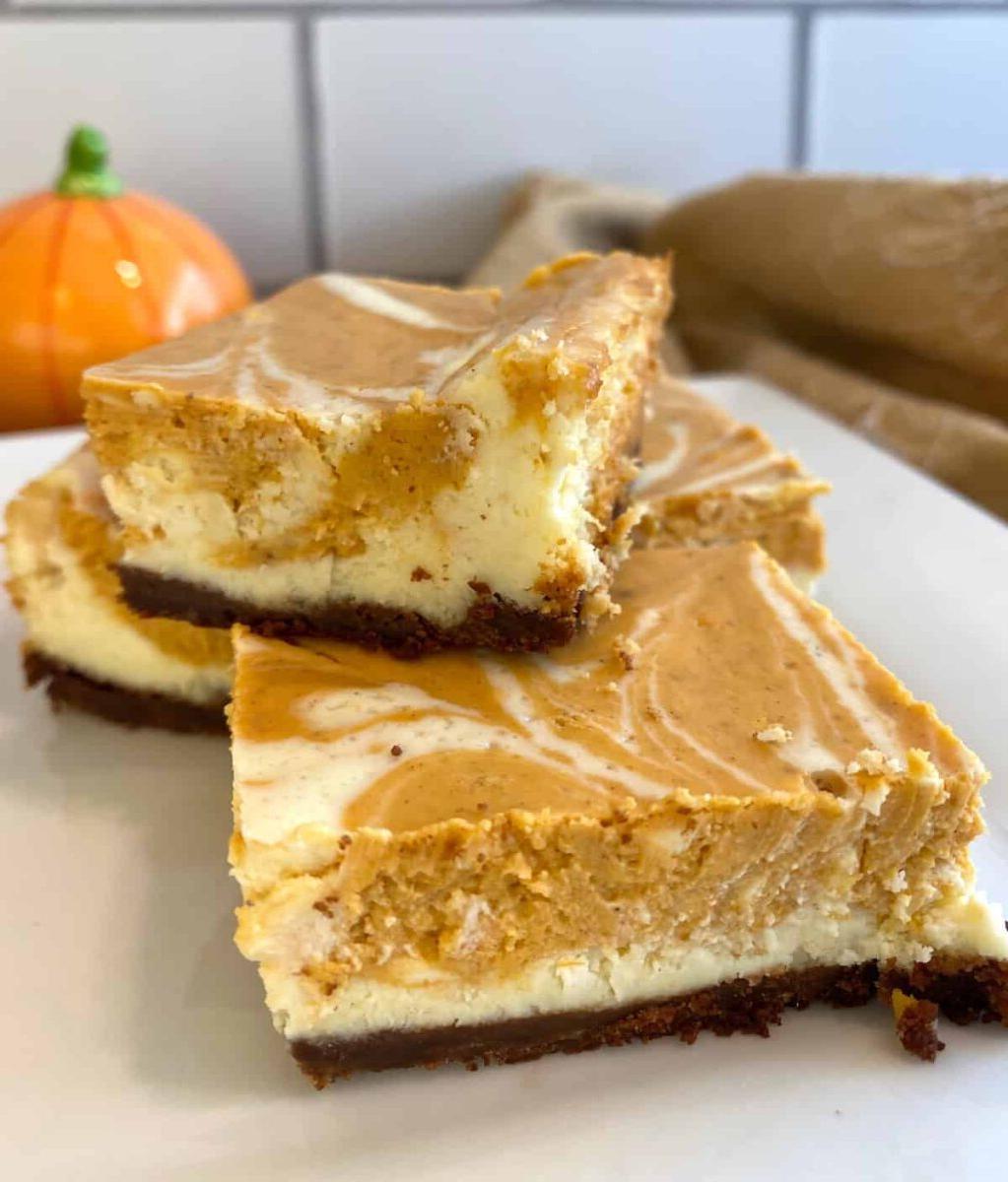 Three baked cheesecake bars stacked on a plate.