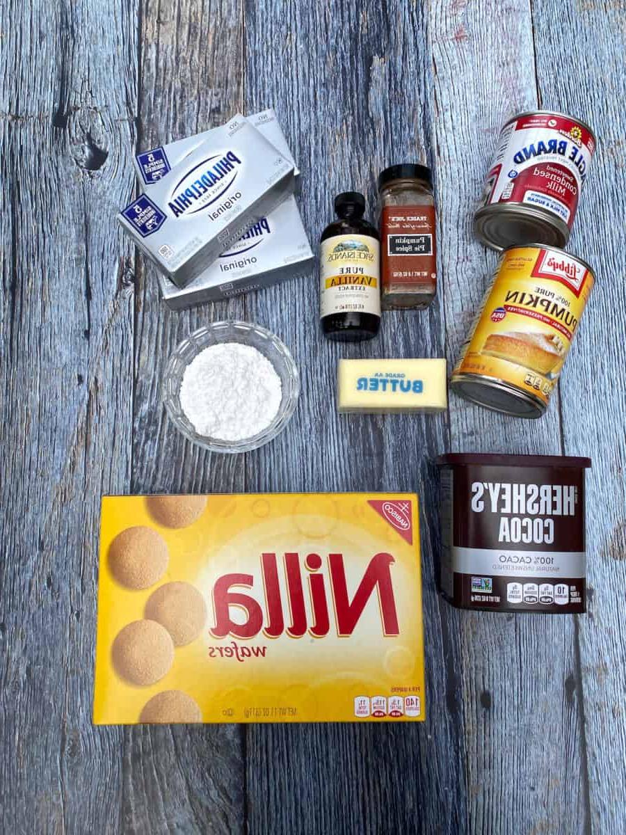 Ingredients for marbled pumpkin cheesecake bars, spread out on a wooden board.