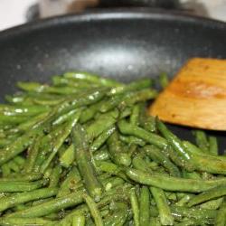 Sautéed seasoned green beans in a black frypan