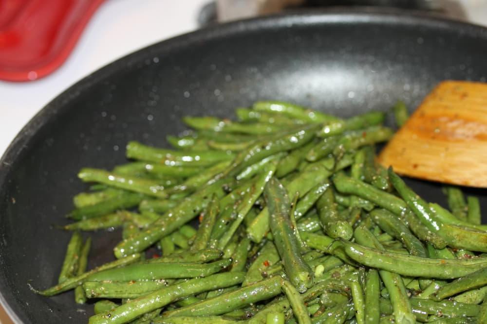 Green Beans Seasoned with Italian Dressing Sautéed seasoned green beans in a black frypan